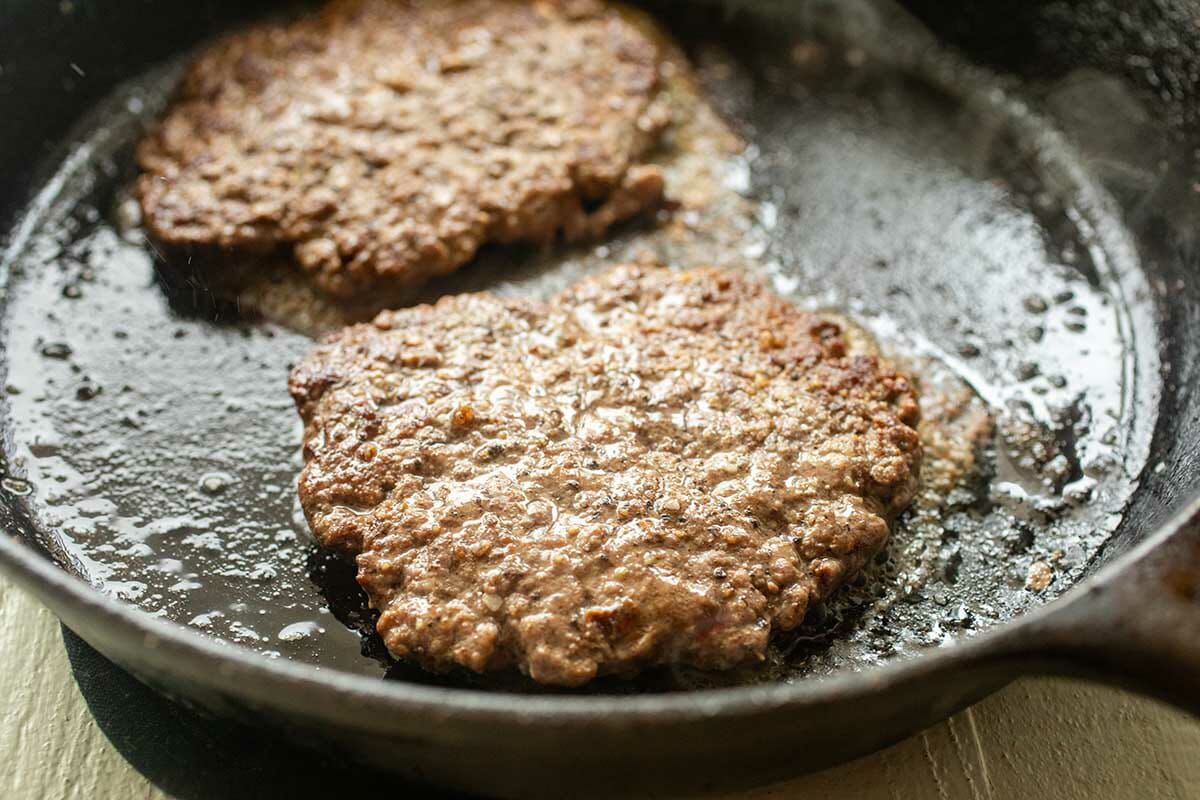 Two beef patties cooked in a cast iron skillet to make the perfect patty melt.