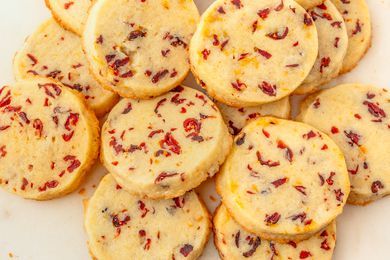 Overhead view of multiple cranberry orange shortbread cookies on an off-white background