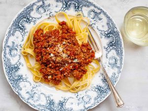 A beautiful fast bolognese sauce on a blue patterned plate with noodles and fork.