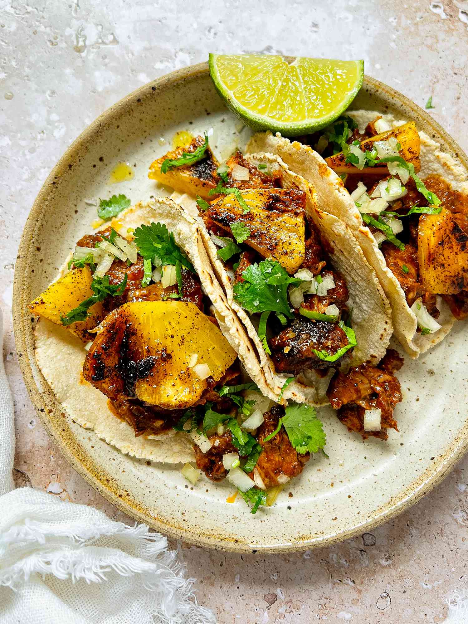 Plate of Tacos al Pastor with Pork, Pineapple, Cilantro, and a Lime Wedge 