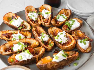 A platter of potato skins topped with cheese and sour cream.