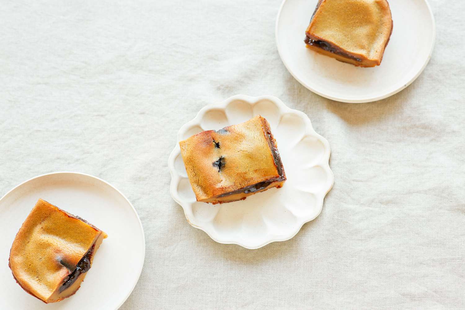 Overhead view of three plates each with a slice of Chinese baked sticky rice cake with red bean paste.