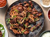 Spicy pork bulgogi on a platter, surrounded by condiment bowls