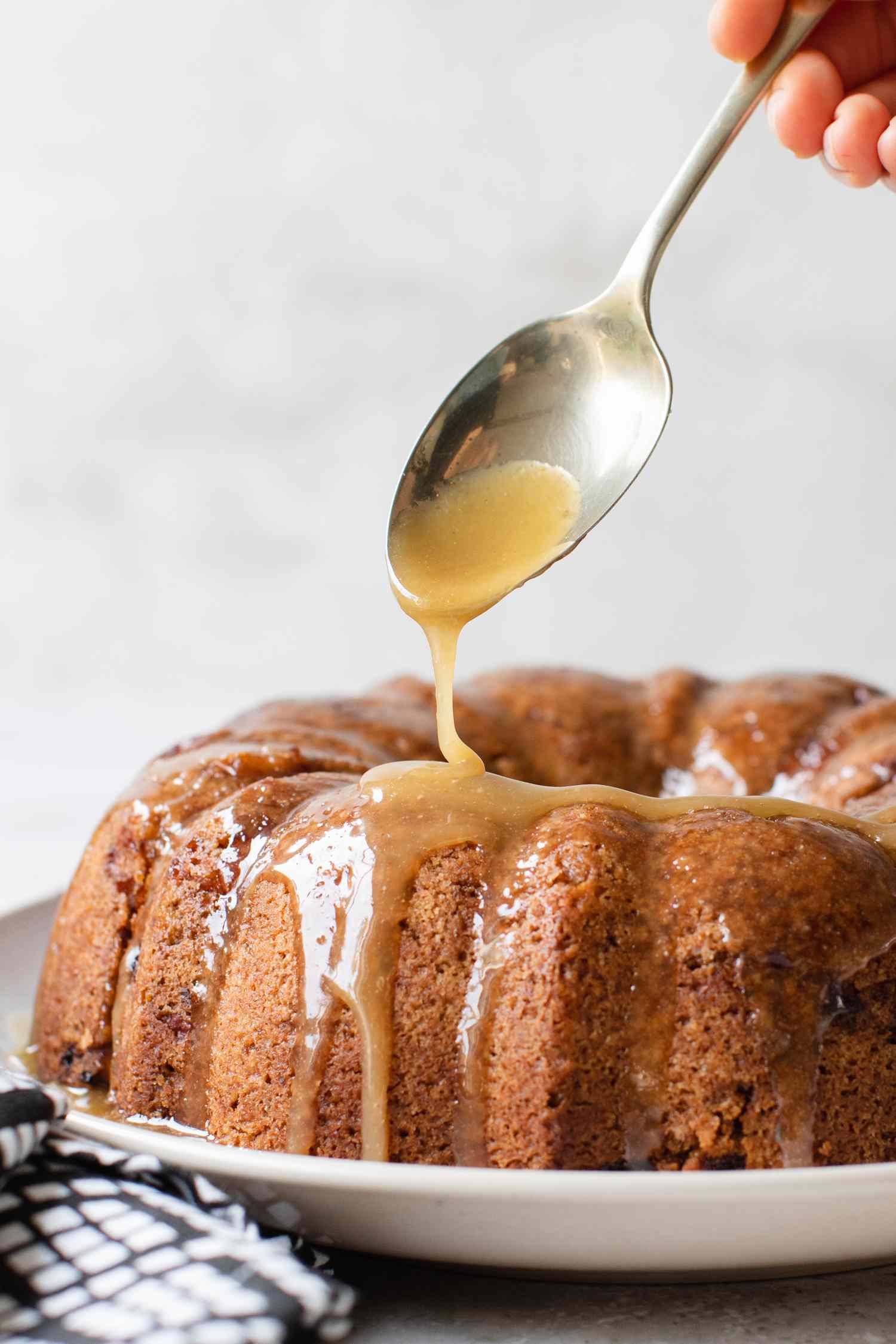 Best Fresh Apple Bundt Cake on a Platter Being Glazed with a Spoon