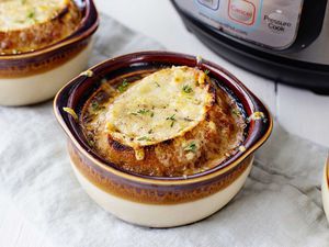 Bowl of French Onion Soup with crusty bread and melted cheese on top with an Instant Pot in the background.