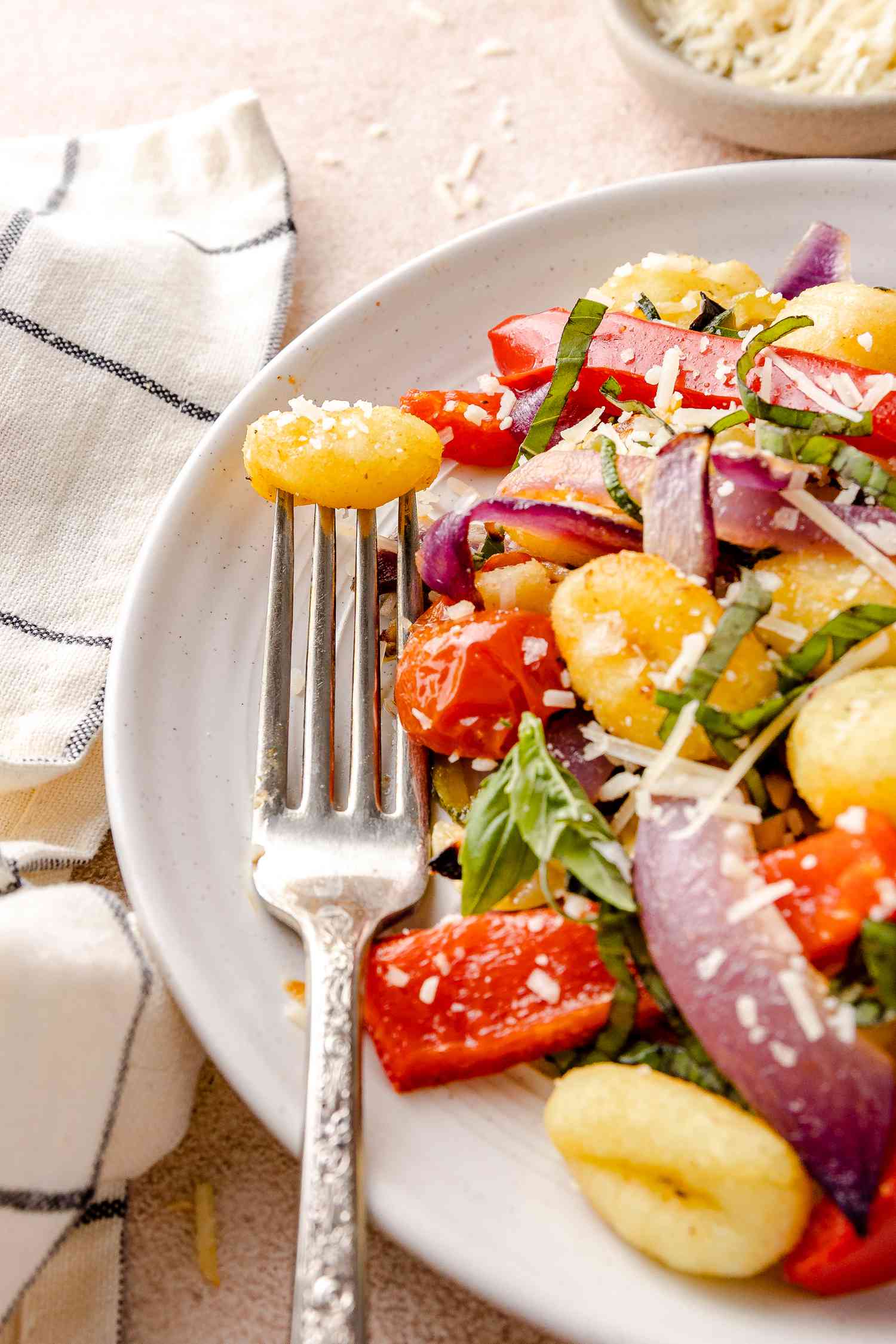 Sheet Pan Gnocchi with Zucchini, Tomatoes, and Bell Peppers on a Plate with a Piece on a Fork
