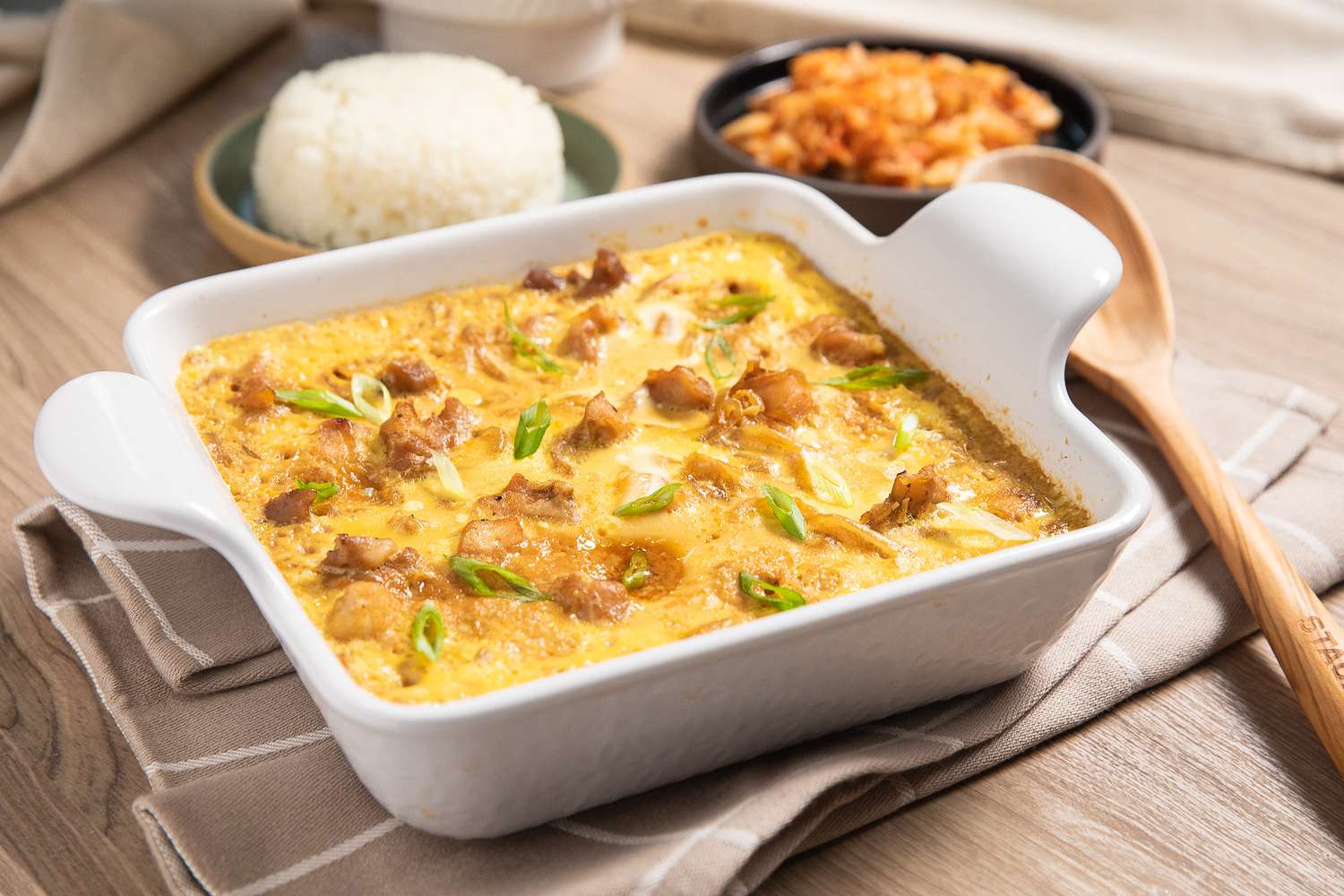 Microwave Oyakodon (Japanese Chicken and Egg Rice Bowl) in a Microwavable Dish, and in the Background, a Small Plate With Cooked Rice and a Small Plate of Kimchi