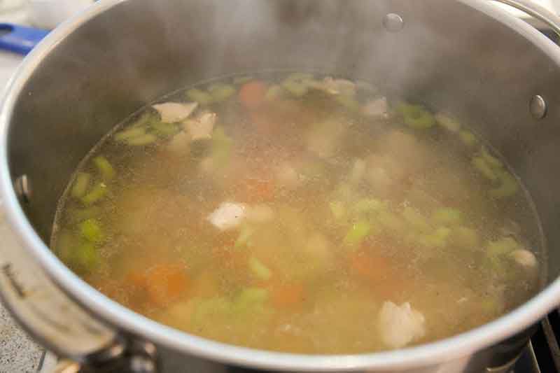 A stockpot of broth for homemade chicken noodle soup.