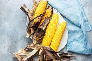A Platter of Grilled Corn on the Cob with Husks Partially Removed