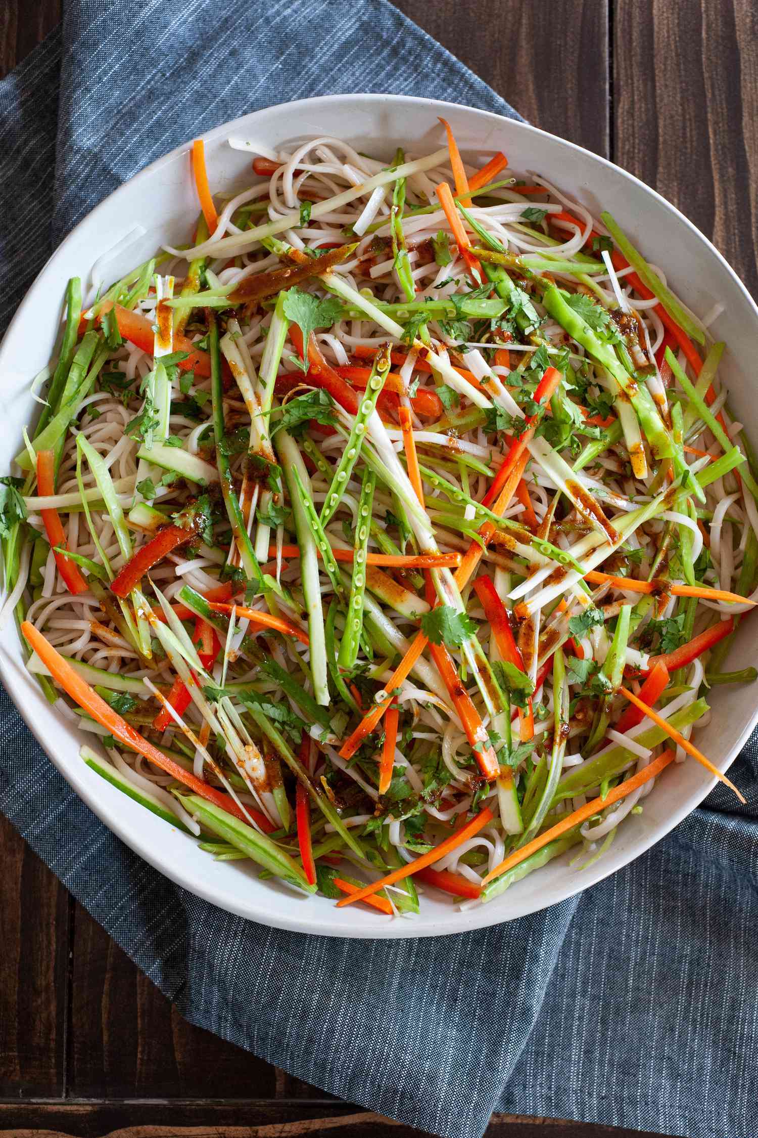 Vegetable rice noodle salad in a serving bowl with a linen underneath.