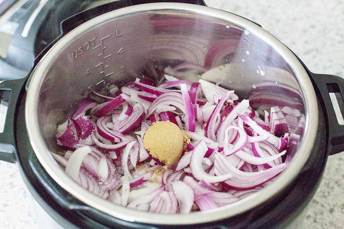 Raw red onions in the bottom of an instant pot bowl for french onion soup.