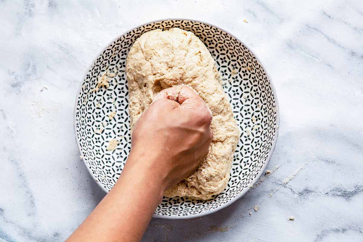 Homemade Naan Recipe - dish with dough and person punching dough