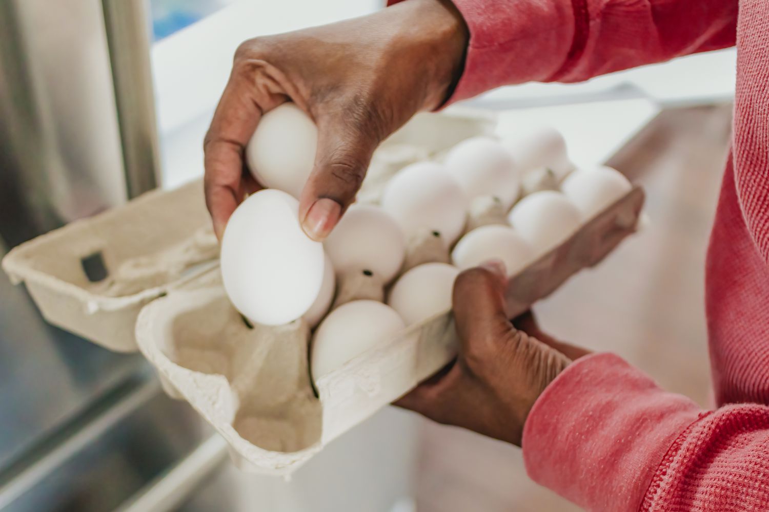 Someone taking eggs out of their carton near the fridge