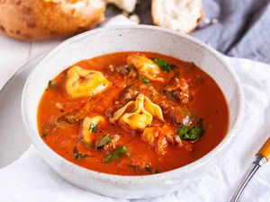 One-Pot Tortellini Soup - white bowl with tomato soup, fresh basil and cheese filled tortellini