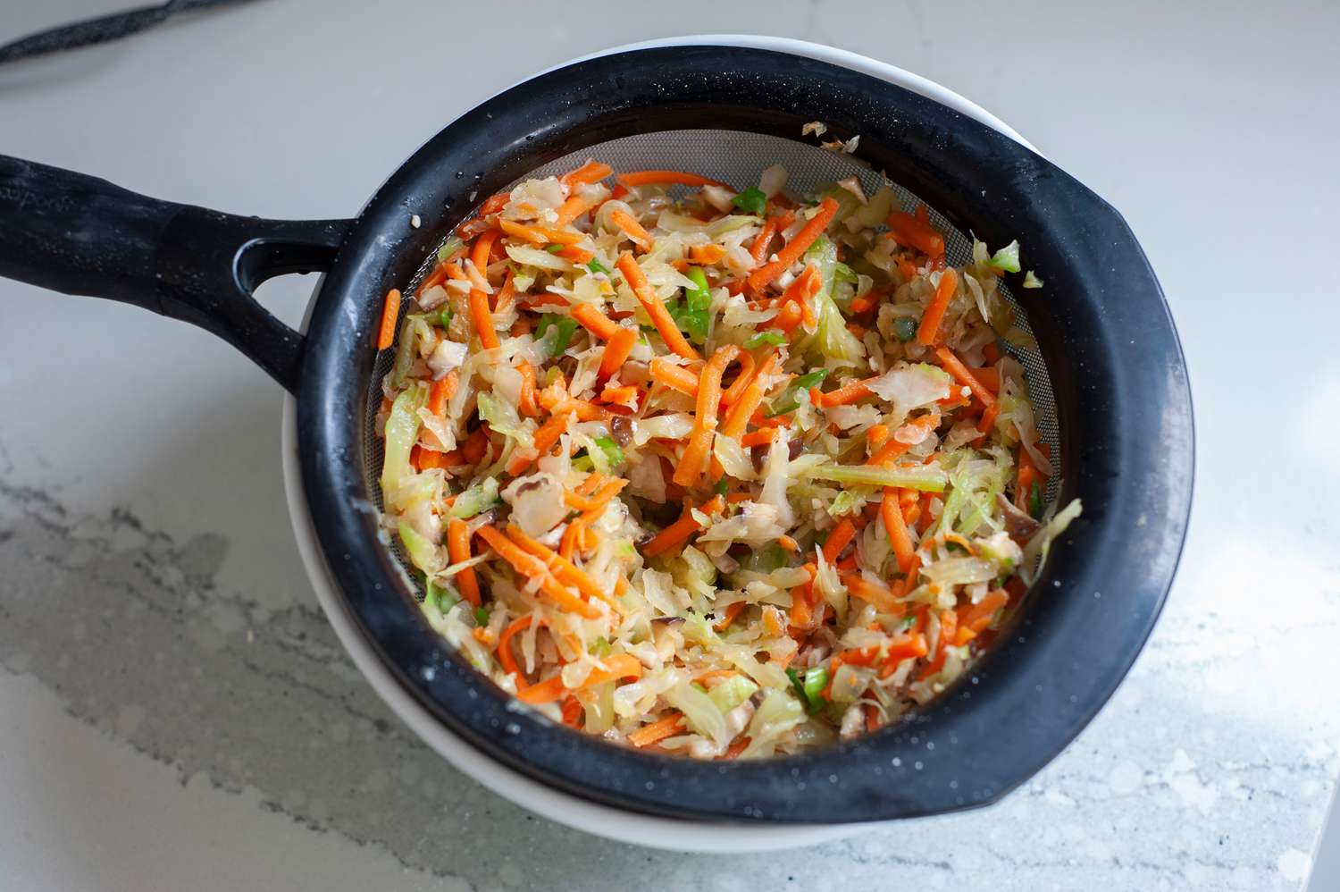 Making the filling for fried egg rolls with cabbage, carrots, and mushrooms in a large pot.