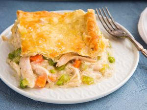 A square slice of the best Chicken Pot Pie is on a plate and the shredded chicken and vegetable filling is visible.