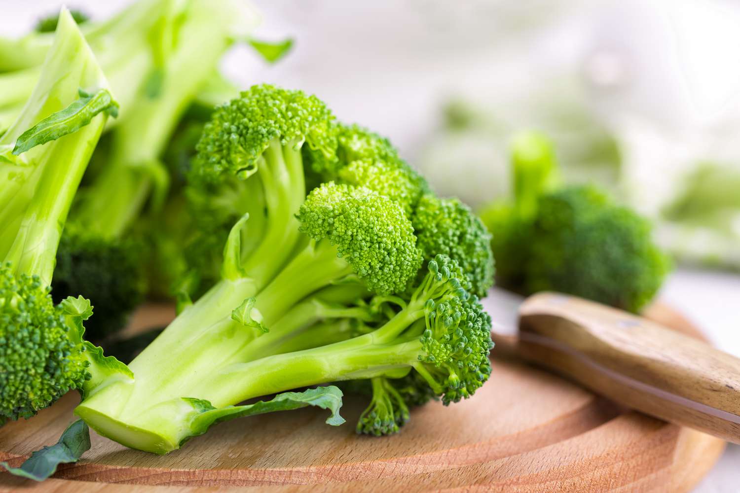 A closeup of a broccoli floret on a wooden cutting board