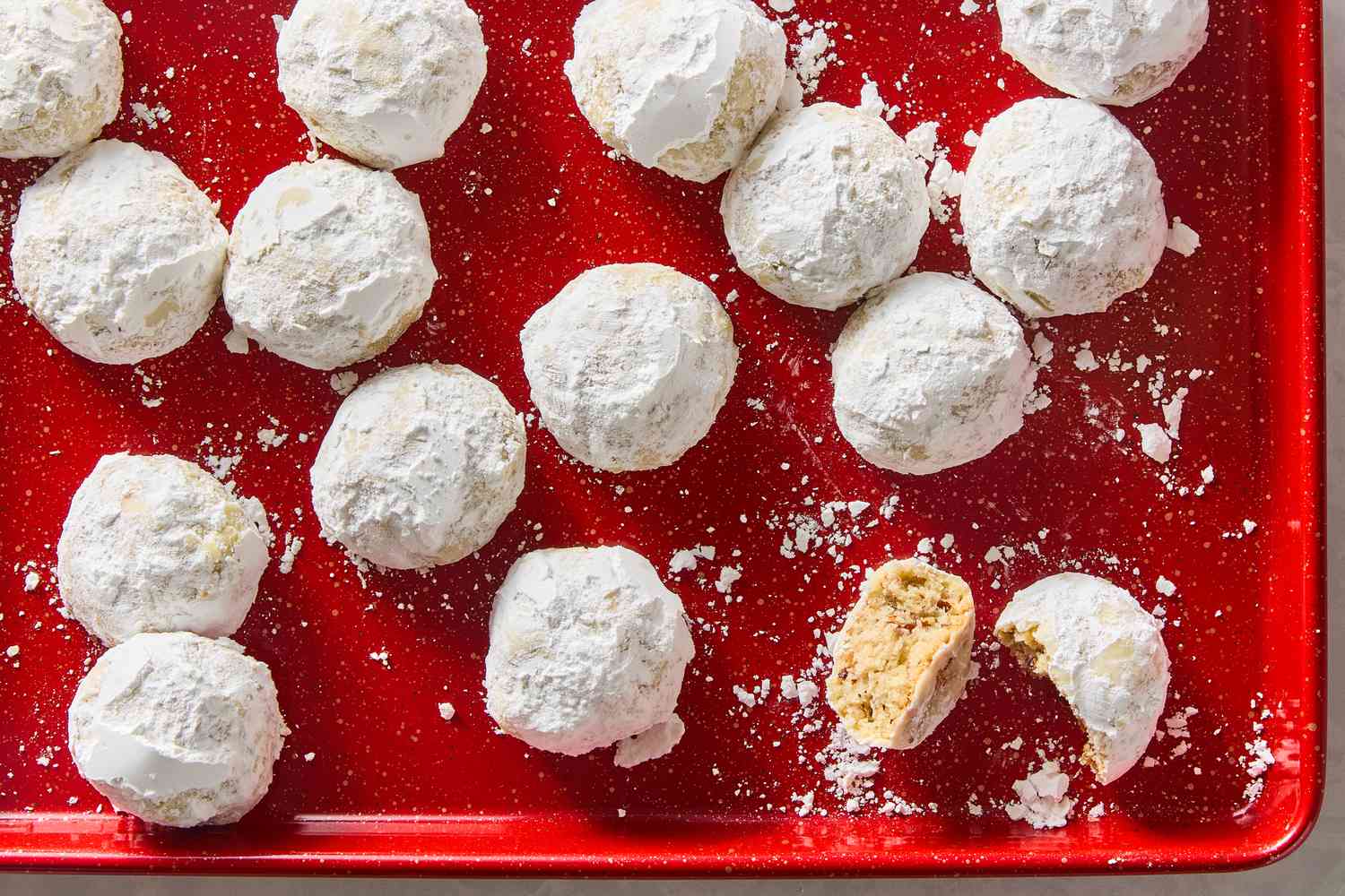 Red baking sheet filled with Mexican Wedding Cookies