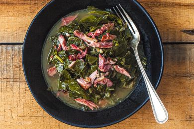 Overhead view of southern collard greens in a black bowl on a wood surface.