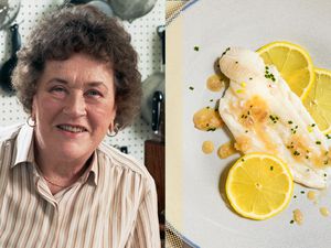 Julia Child next to a plated fish dish with lemon slices