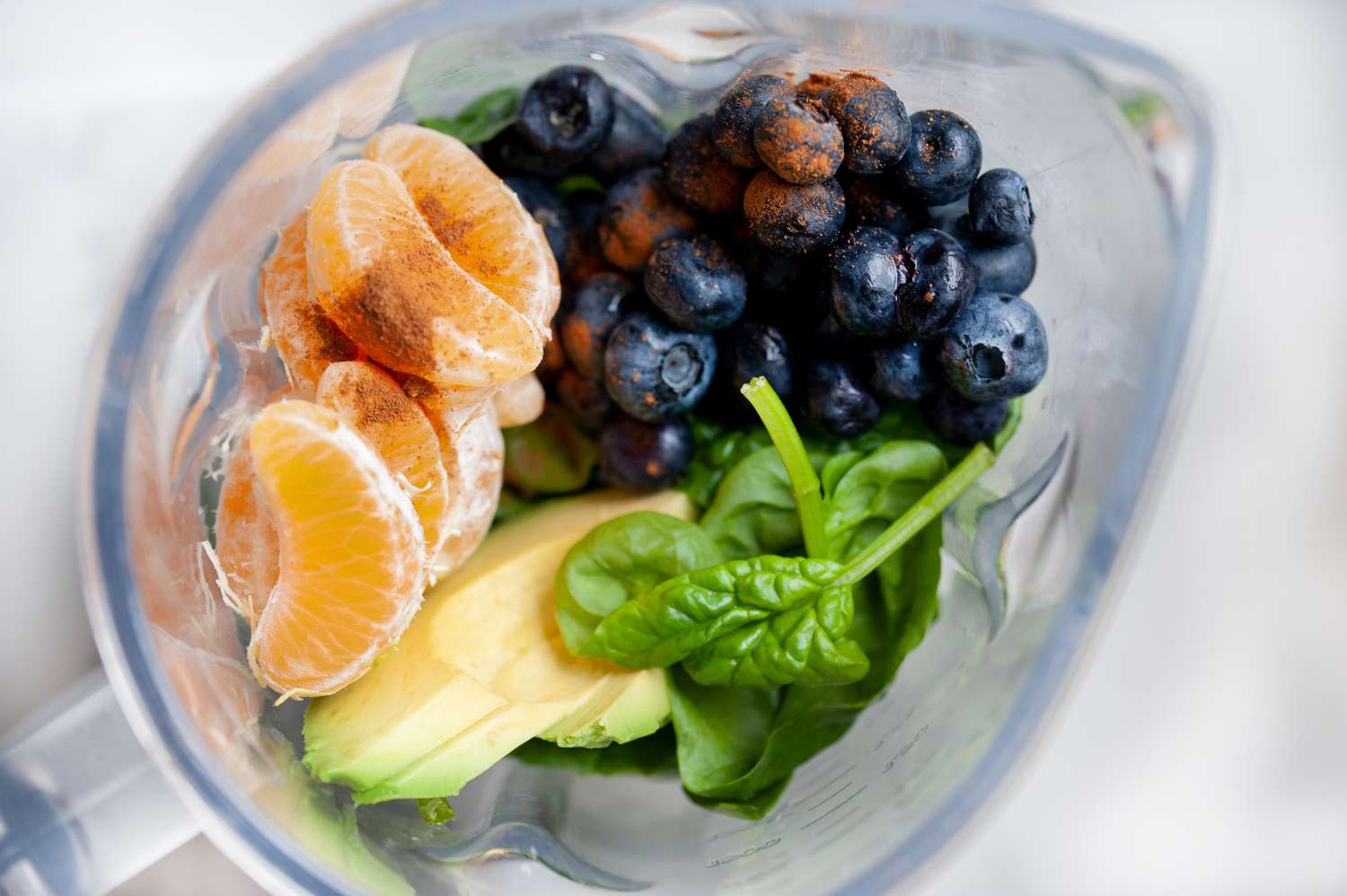 Overhead view of fresh fruit in a blender to make a blueberry smoothie recipe.