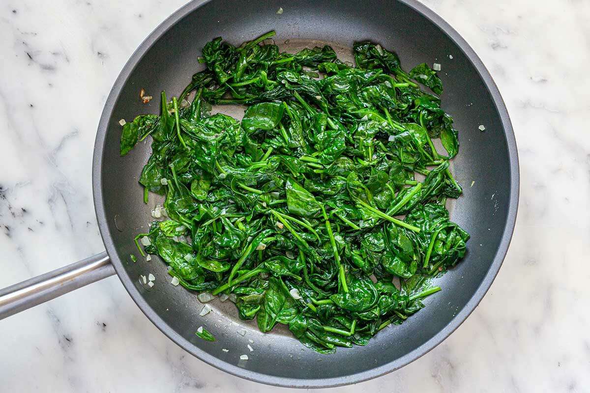 Sauteed spinach in the bottom of a non-stick skillet to make the Best Creamed Spinach.