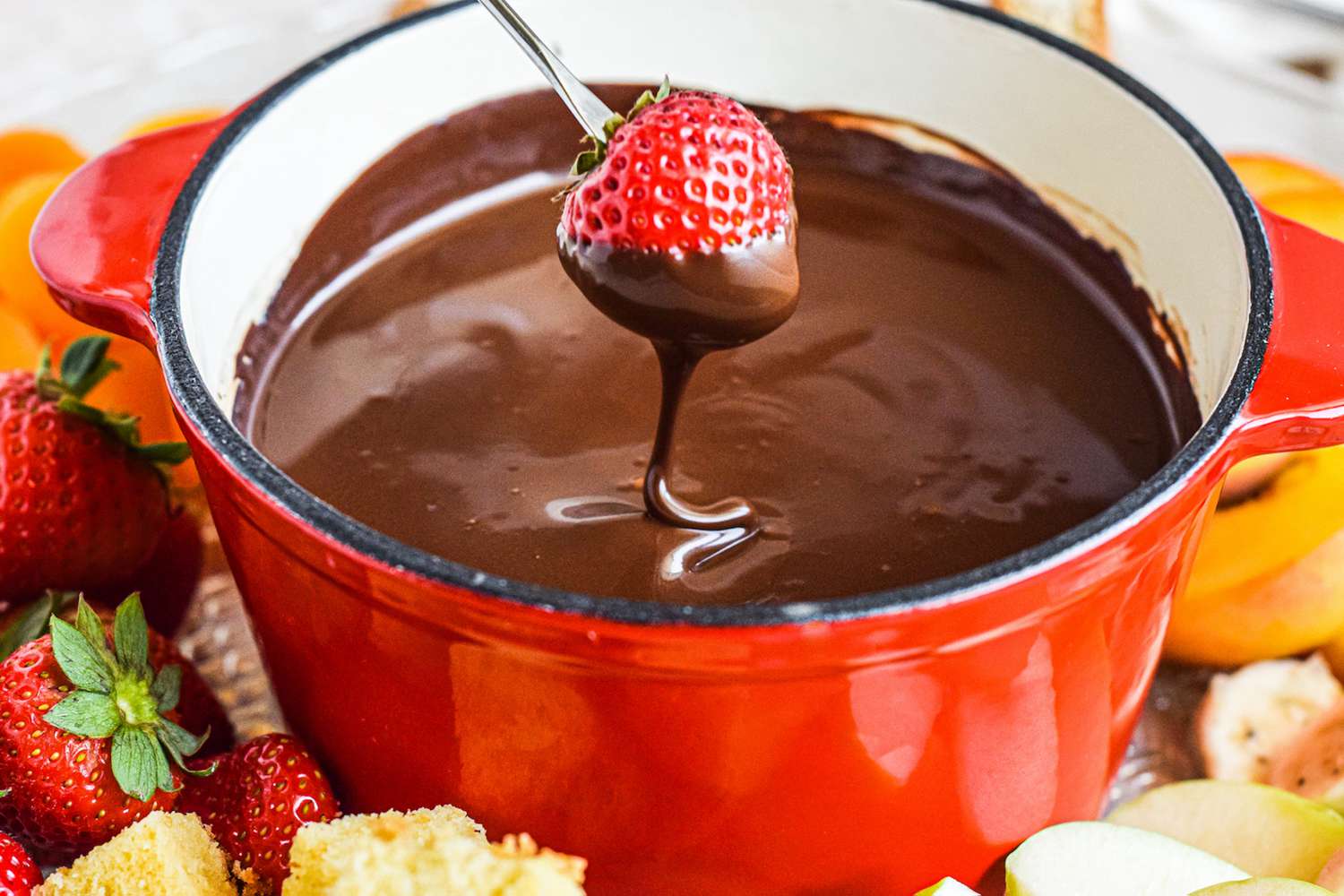 Dipping a strawberry into fondue chocolate with other dippers surrounding