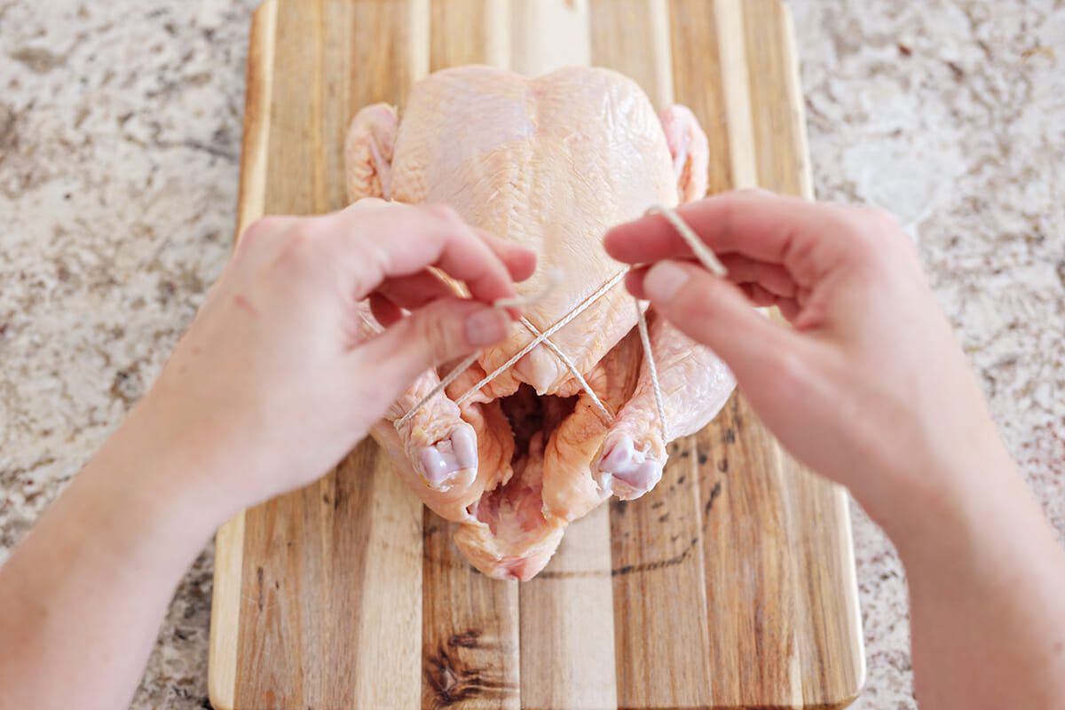 How do I truss a chicken? pull the twine under the legs 
