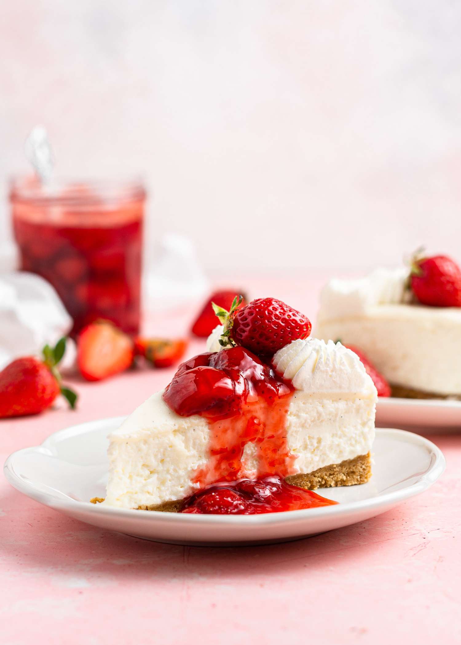 A slice of cheesecake with no bake cheesecake filling topped with strawberry preserves.
