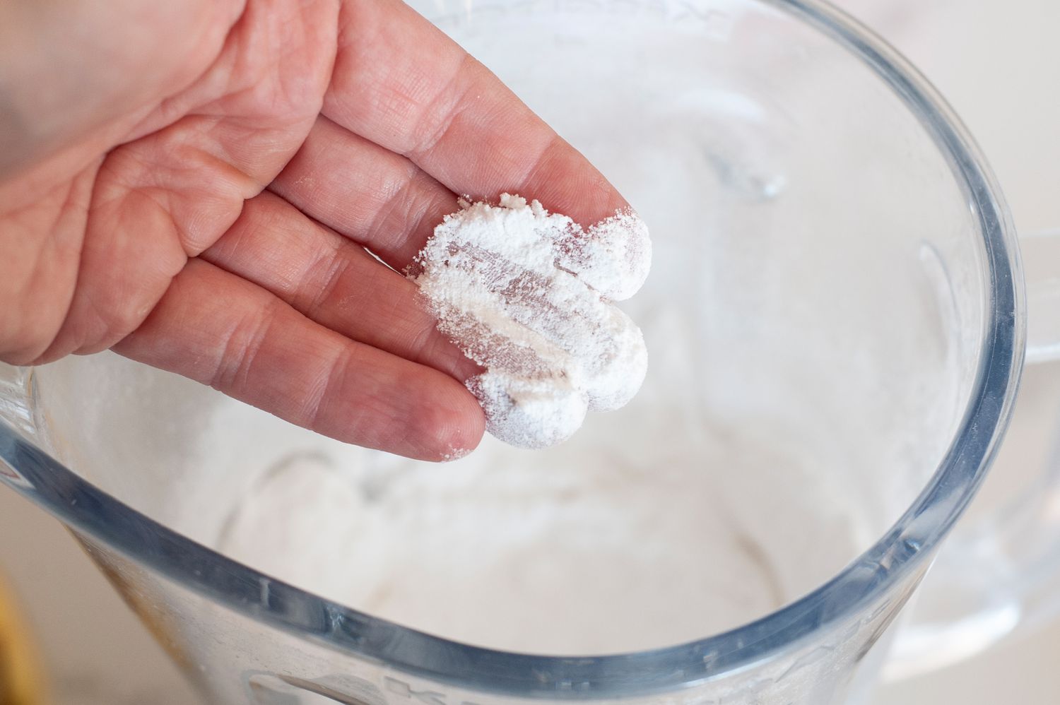 Fingers checking texture of homemade powdered sugar