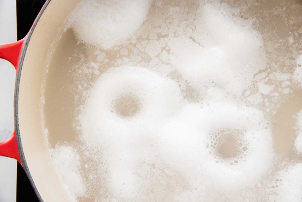 A dutch oven has water and chunks of salt cod simmering inside.