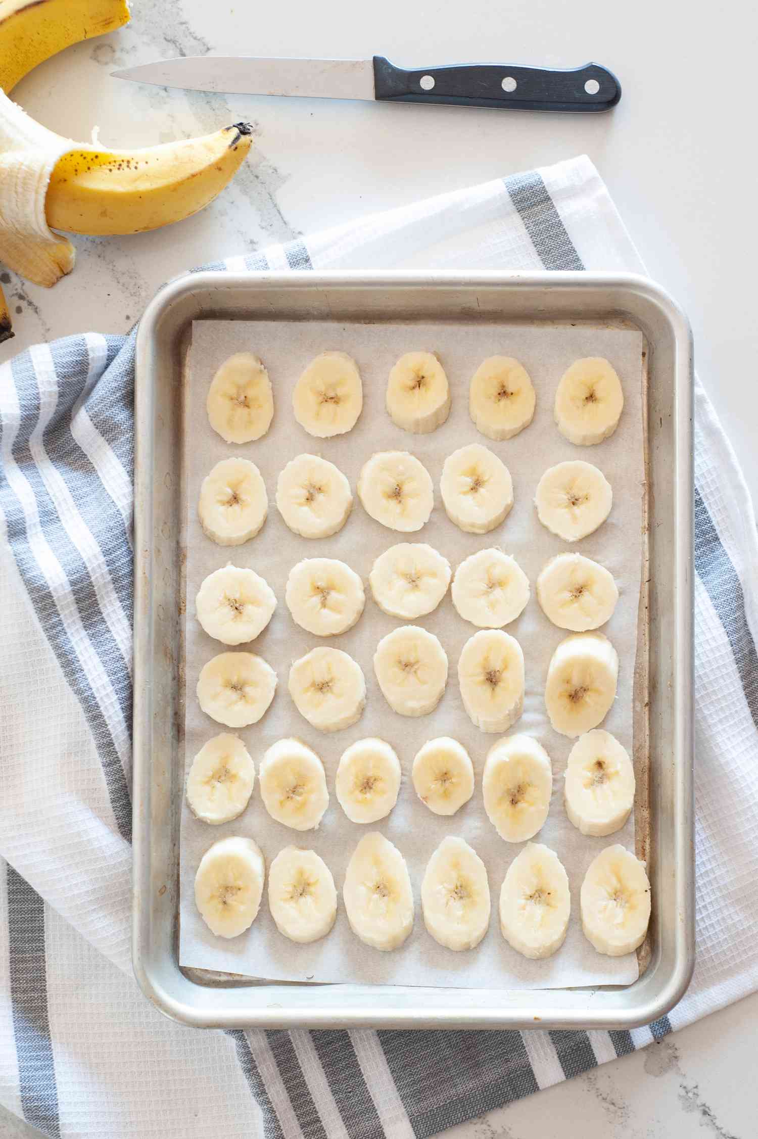 Sliced bananas on a half sheet pan