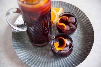 Best Fruity Sangria Recipe - orange slices in a pitcher of sangria on a silver tray with two poured glasses of sangria