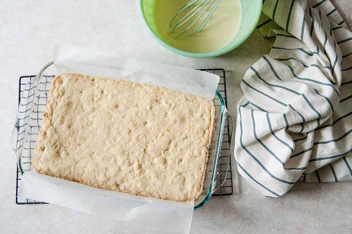 Homemade Lemon Bars - short bread crust in 9x13 pan with bowl of lemon curd nearby