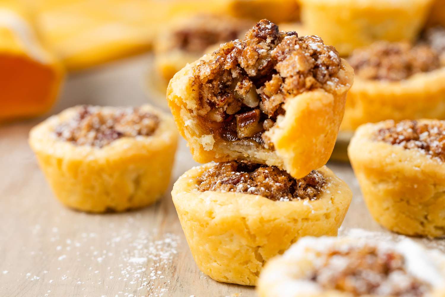 Two pecan pie cookies or tassies stacked up with a bite taken out of the top one