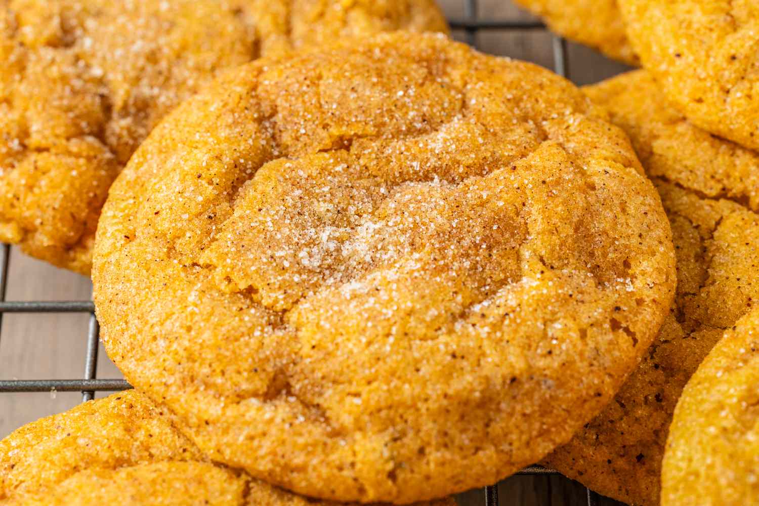 Pumpkin spice snickerdoodle cookies topped with pumpkin spice sugar mixture on a cooling rack