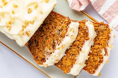 carrot cake loaf on a platter with some sliced pieces splayed onto the platter