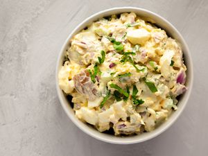 A bowl of creamy potato salad garnished with parsley