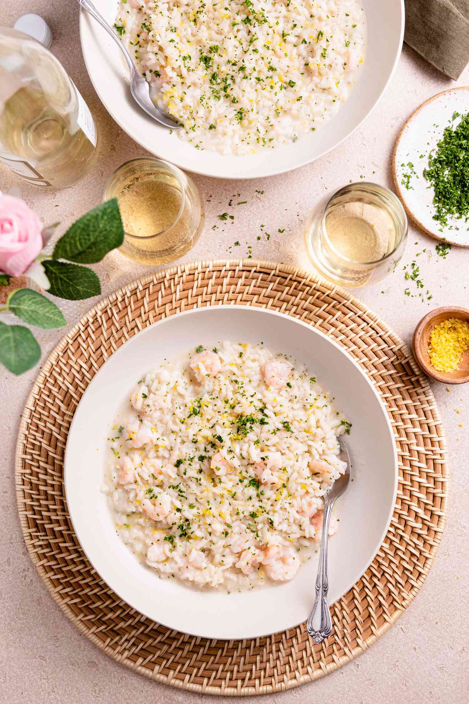Plate of Shrimp Risotto Surrounded by Glasses of Wine, Plate of Herb, and Bowl of More Risotto