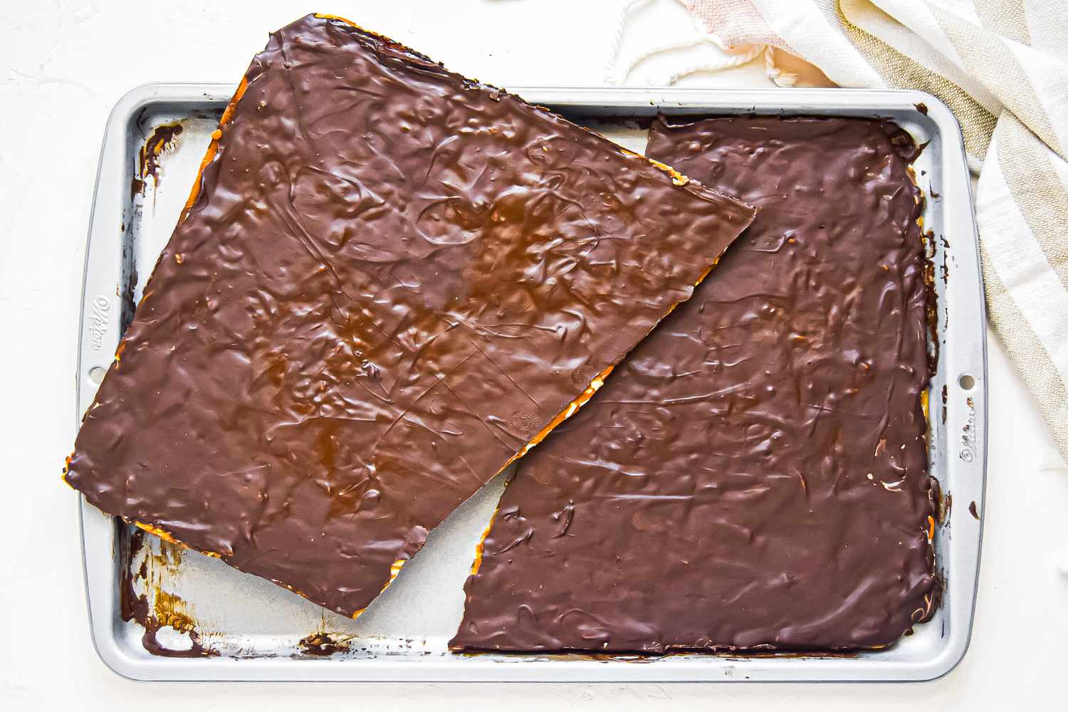 A large sheet of almond roca split in half on top a baking sheet.